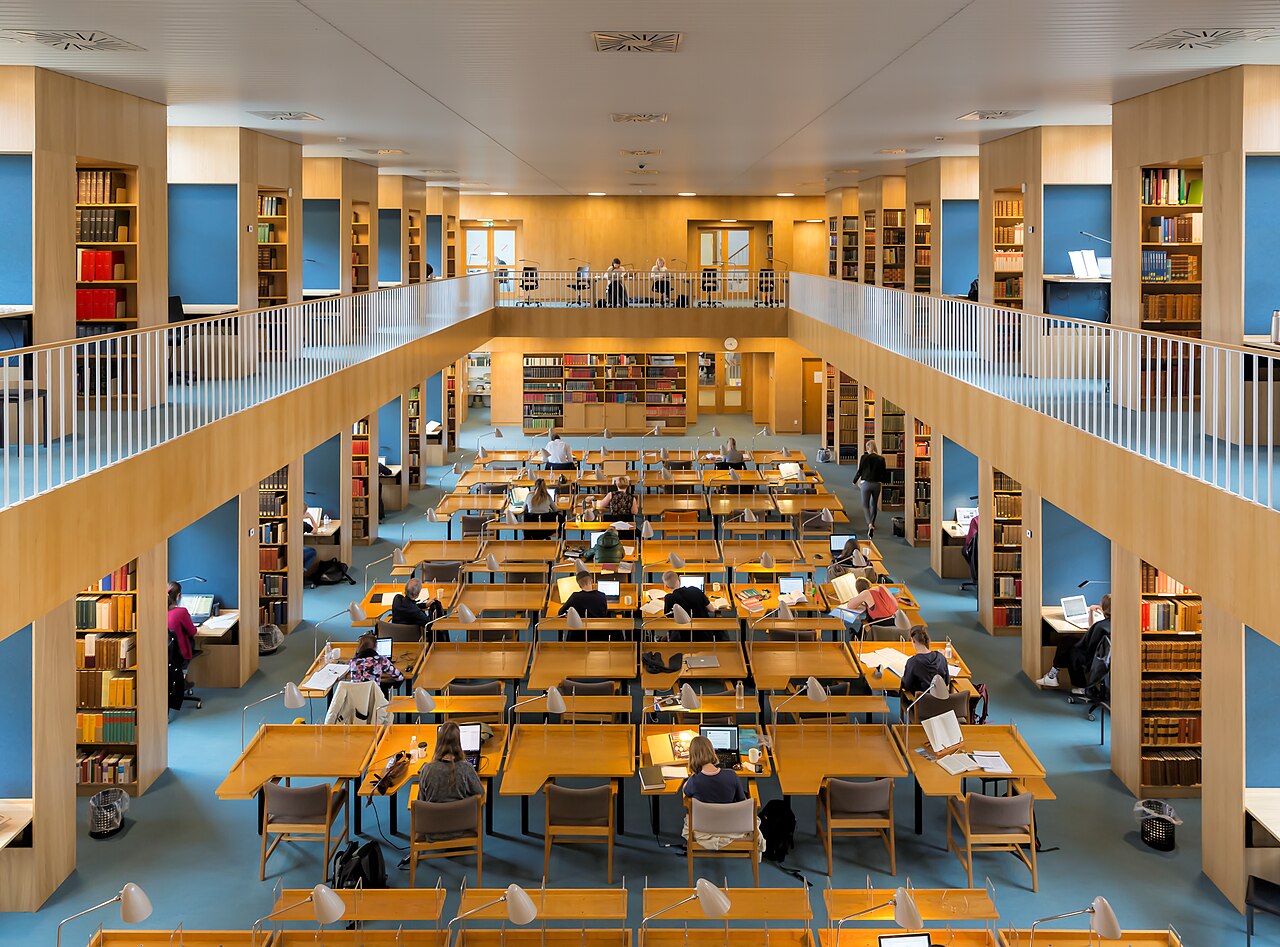 Students studying at long desks in a library reading room